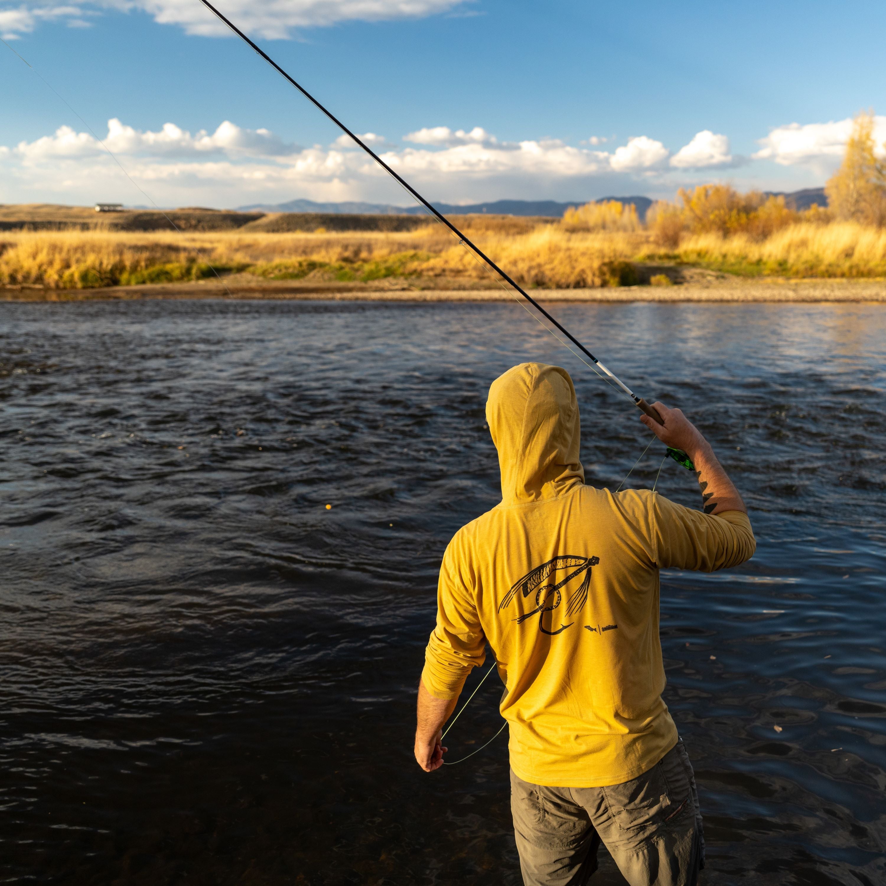 man in water fishing with banjo fly sun hoody merino breeze infamous string dusters collaboration