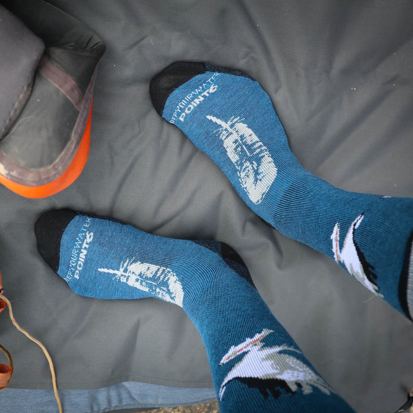 Sock with Osprey design carrying a fish. the top of the foot has a feather in gray