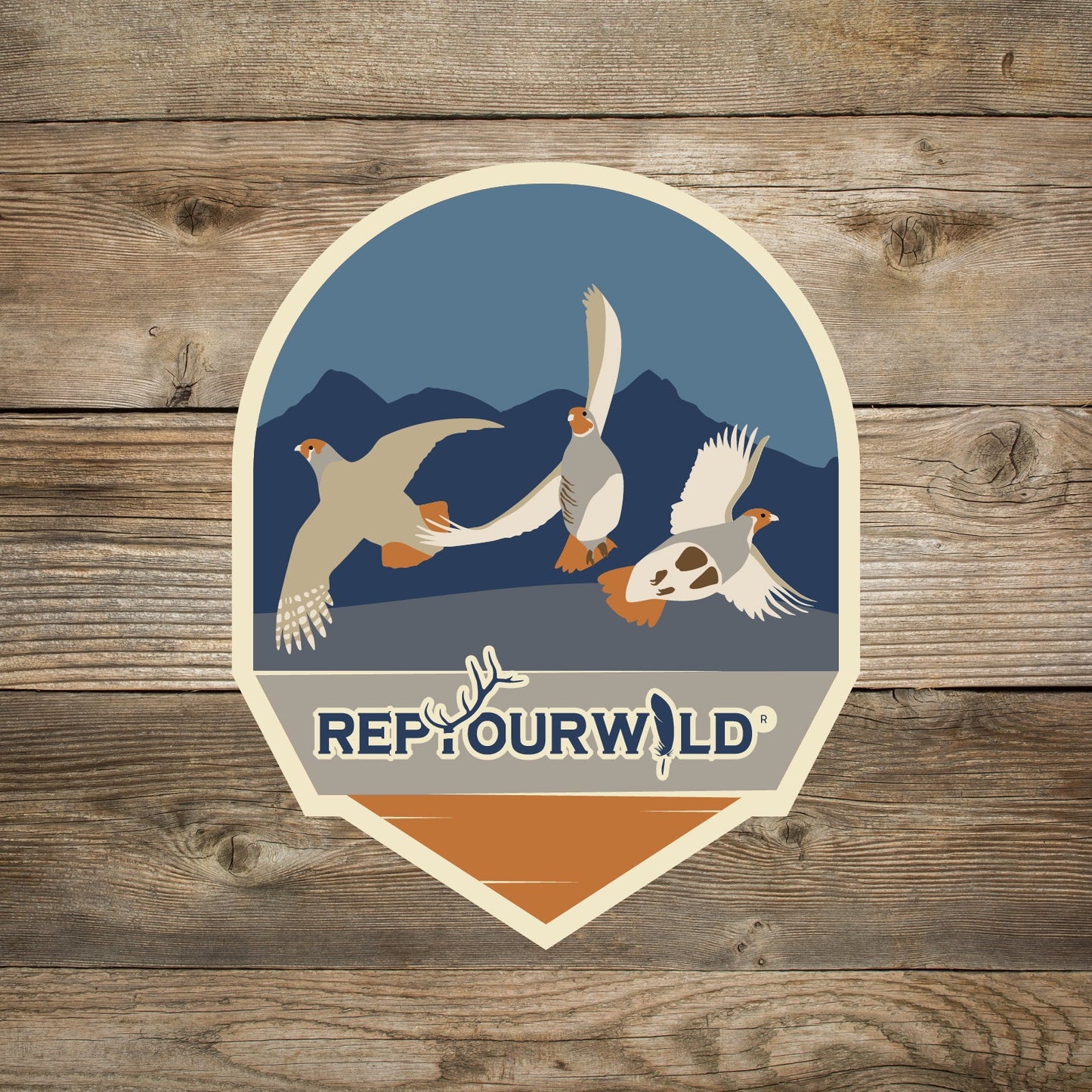 Sticker Round with pointed bottom Blue background with mountains 3 flying grouse words rep your wild at the bottom