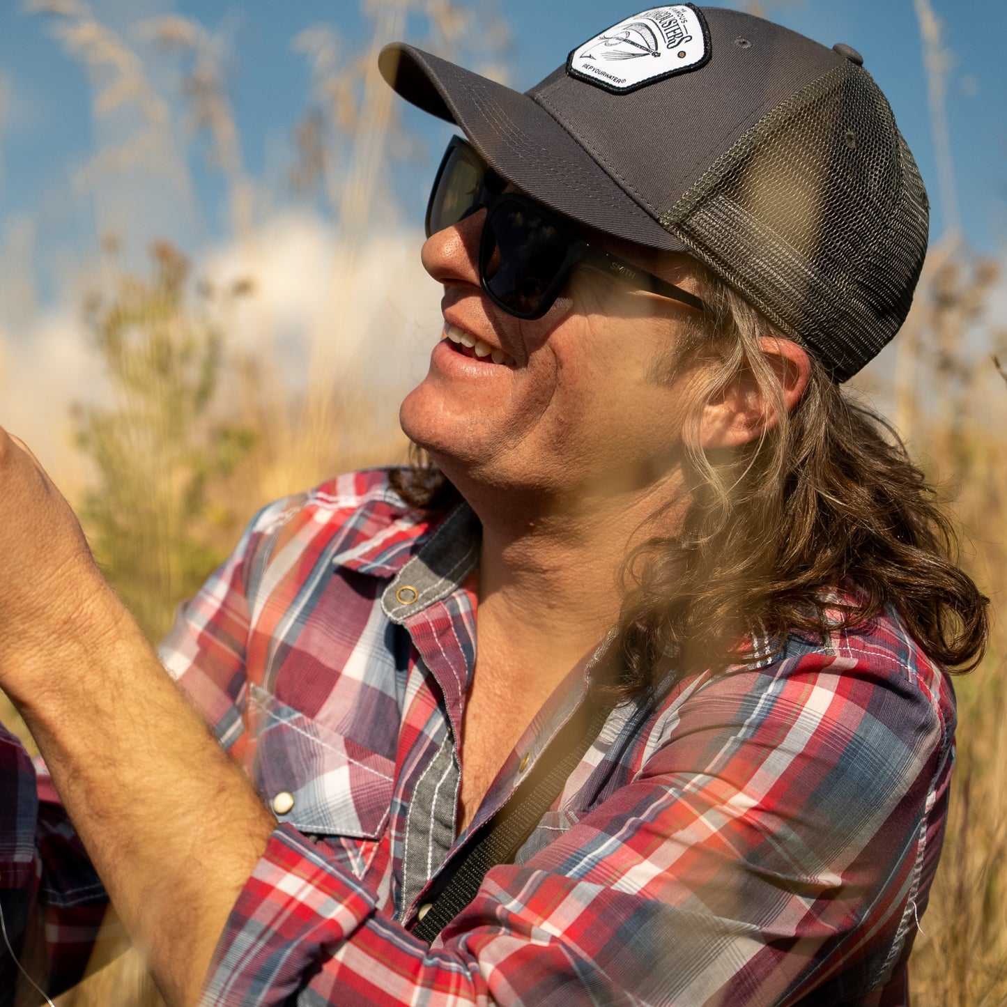 man wearing repyourwater and infamous stringduster collab hat dark green mesh back and gray front with banjo fly hat on the front