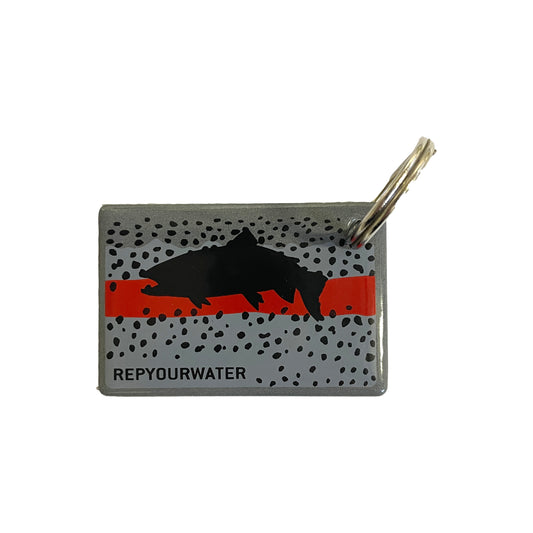 a rectangular key ring shows a black trout on top of a rainbow trout inspired design