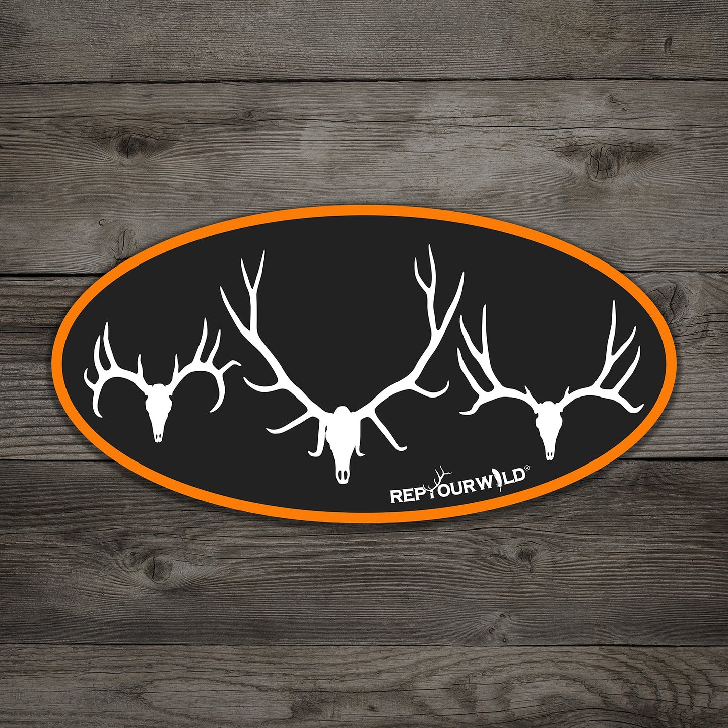 black oval sticker with orange border showing a mule deer skull, elk skull, and whitetail skull in white