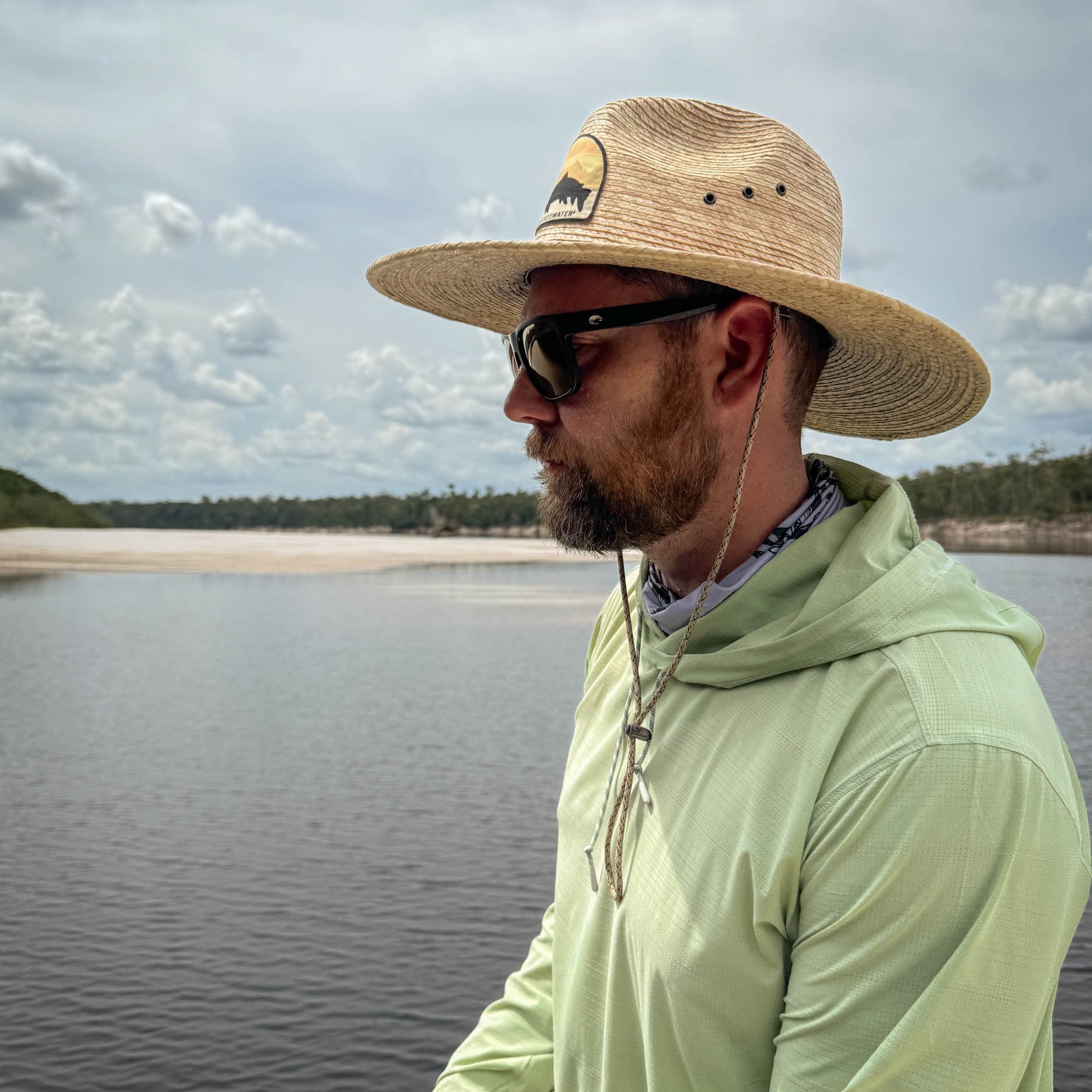 man wearing the punta pescado sun hat with a green hoody on the water