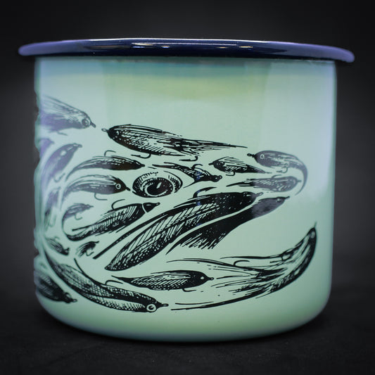 Photo of a teal ceramic mug with hints of royal blue with a pen and ink drawing of a trout head made up of fishing flies