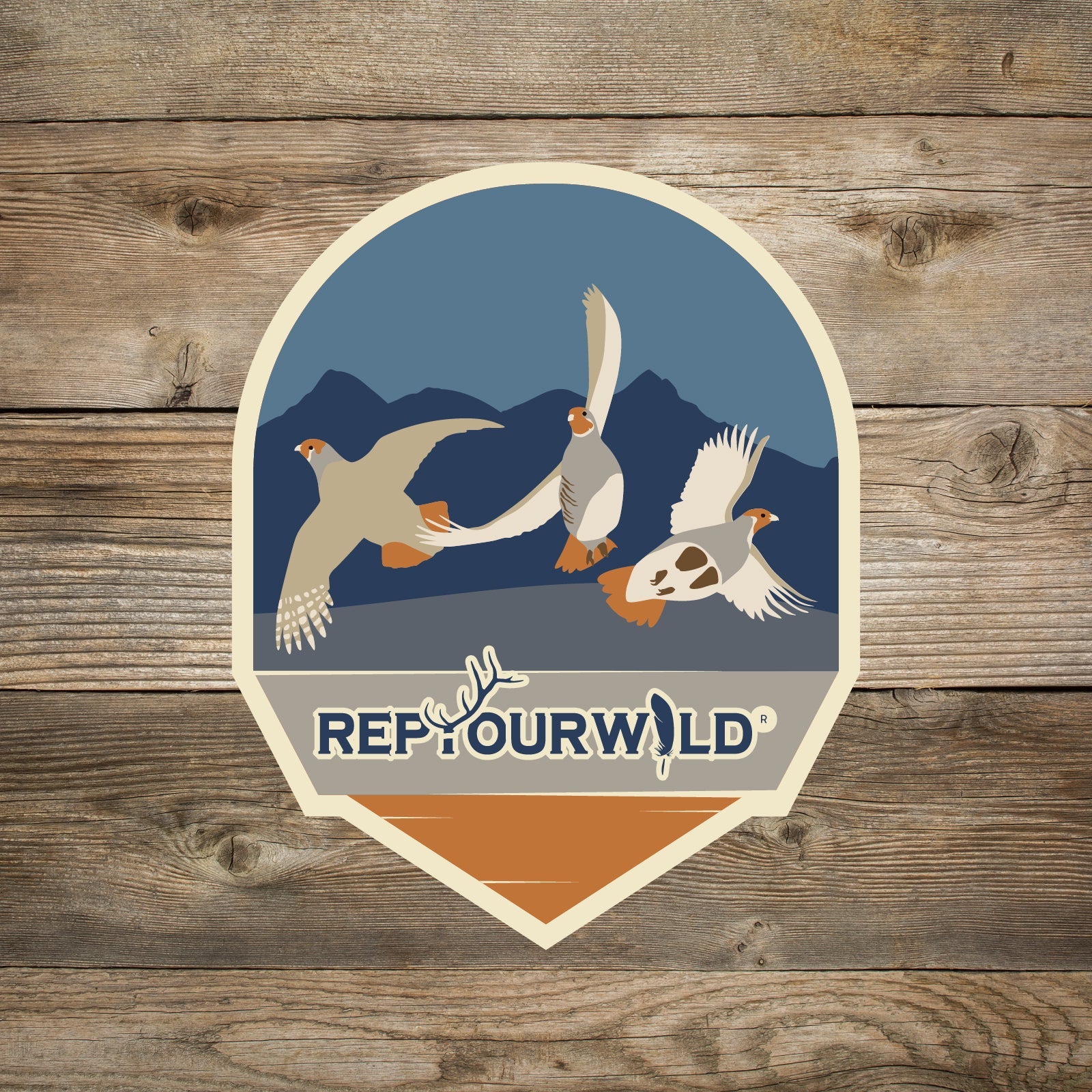 Sticker Round with pointed bottom Blue background with mountains 3 flying grouse words rep your wild at the bottom
