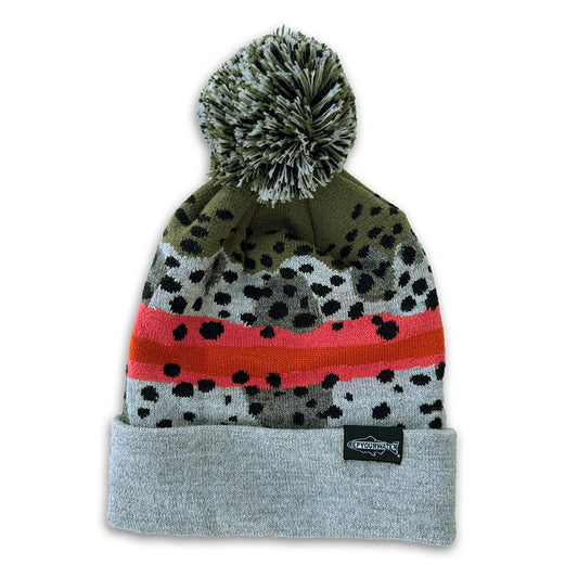 A winter hat imitating rainbow trout skin with a gray and green poof on top and a light grey cuff