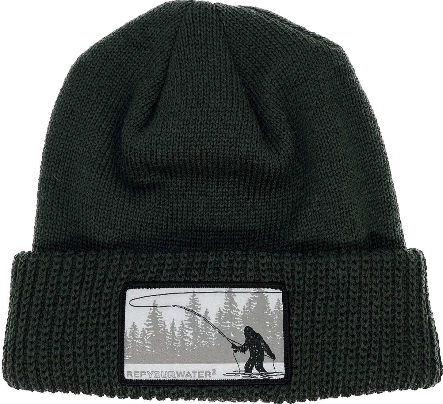 A dark forest green winter hat with a cuff and a rectangular patch of a sasquatch casting with a line of trees in the background