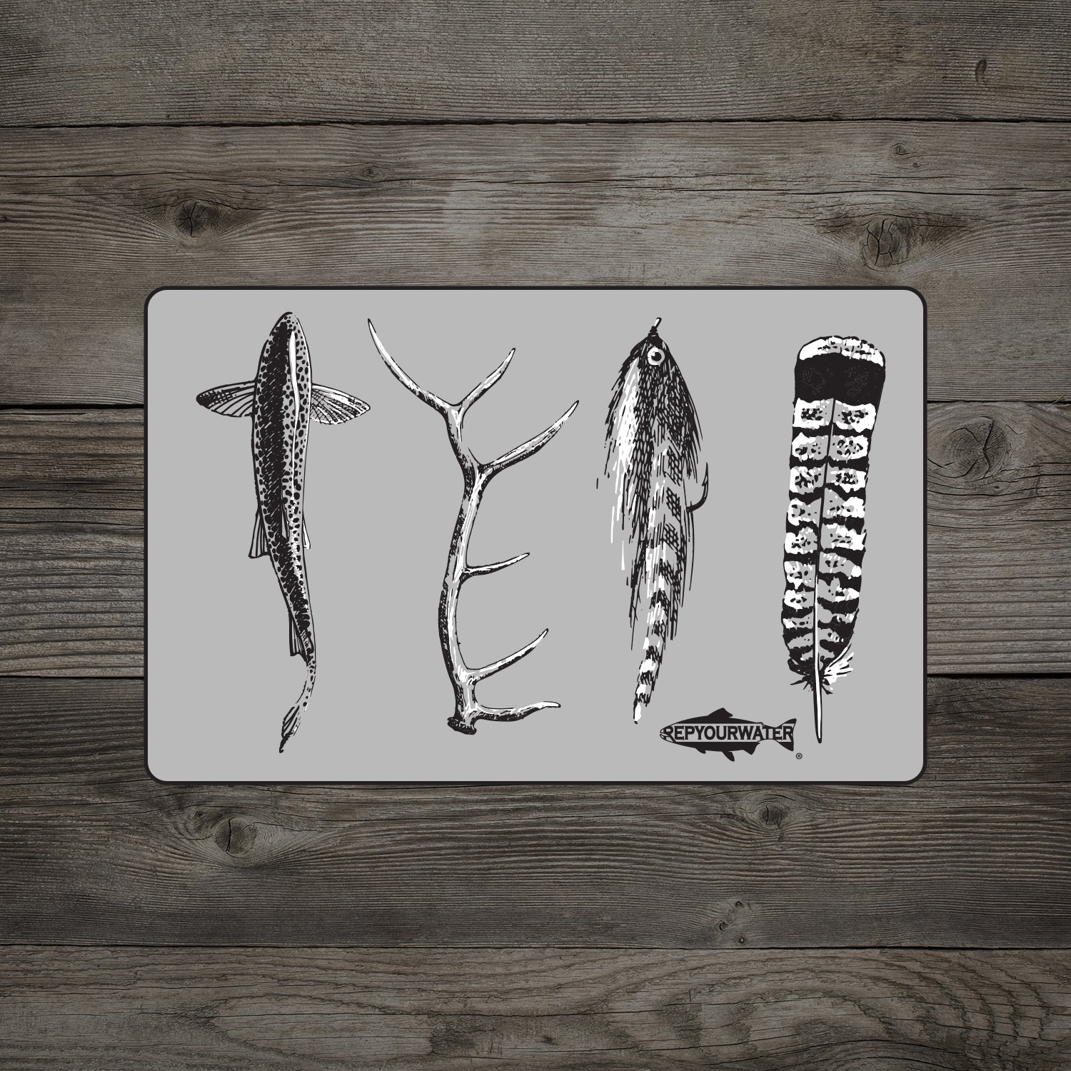 A sticker mockup is shown on a wood background the sticker shows a trout antler streamer and feather on a gray rectangular shape there is a fish logo that says rep your water in the middle on the bottom