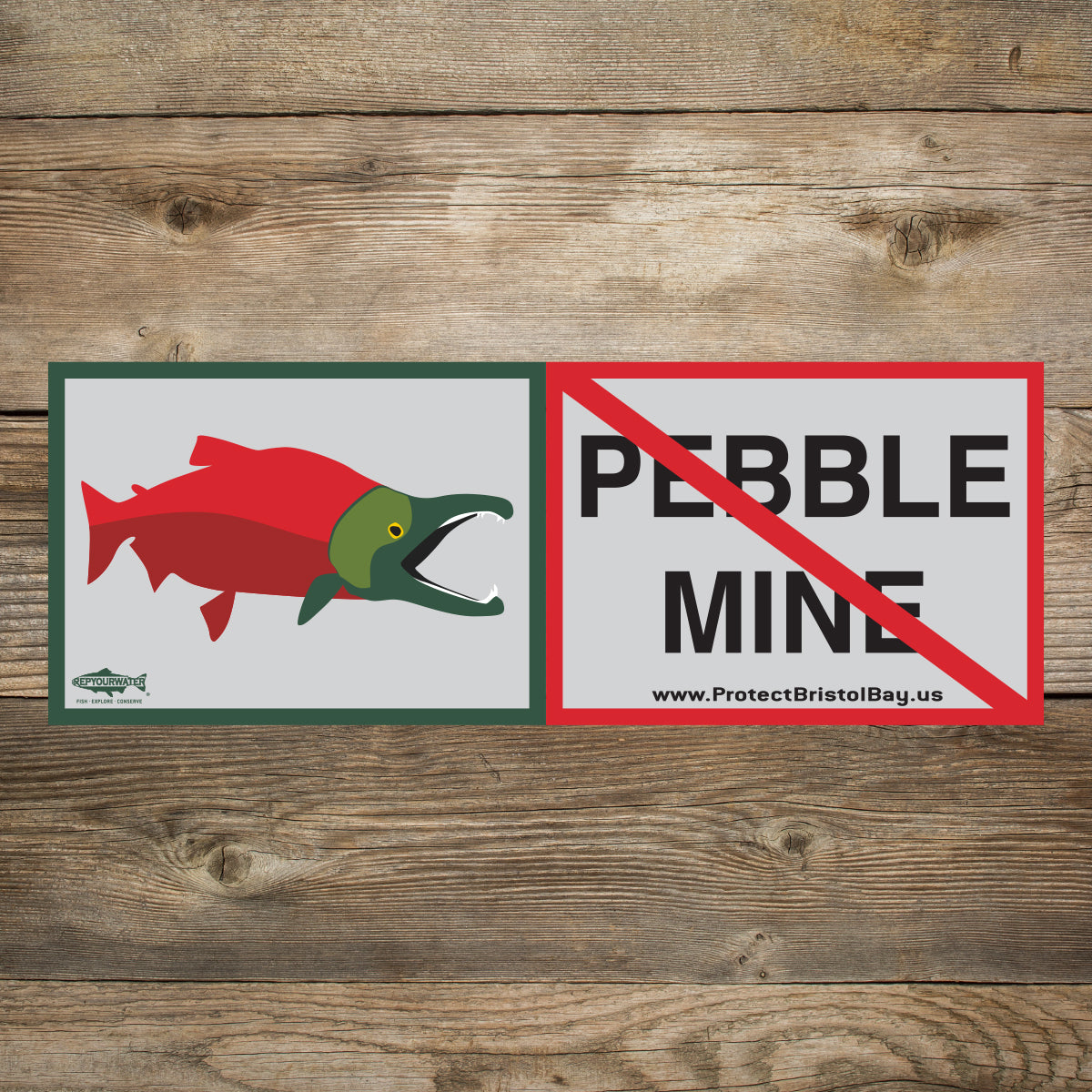 A wood background has a sticker that has a sockeye salmon on one side and the words pebble mine crossed out on the other side.  The website www.protectbristolbay.us is written and a logo that says repyourwater inside a trout silhouette with the words fish explore conserve is below the salmon