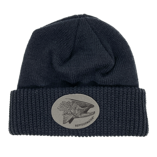A dark navy winter hat with a cuff and a oval patch on the cuff with a pen and ink rainbow head in it