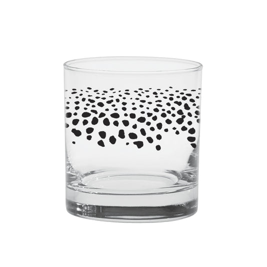 A low ball cocktail glass with spots around it imitating brown trout spots