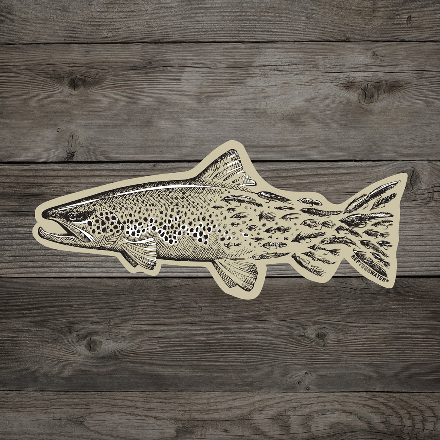 wood background with tan sticker of a brown trout that transitions into fishing flies towards the tail