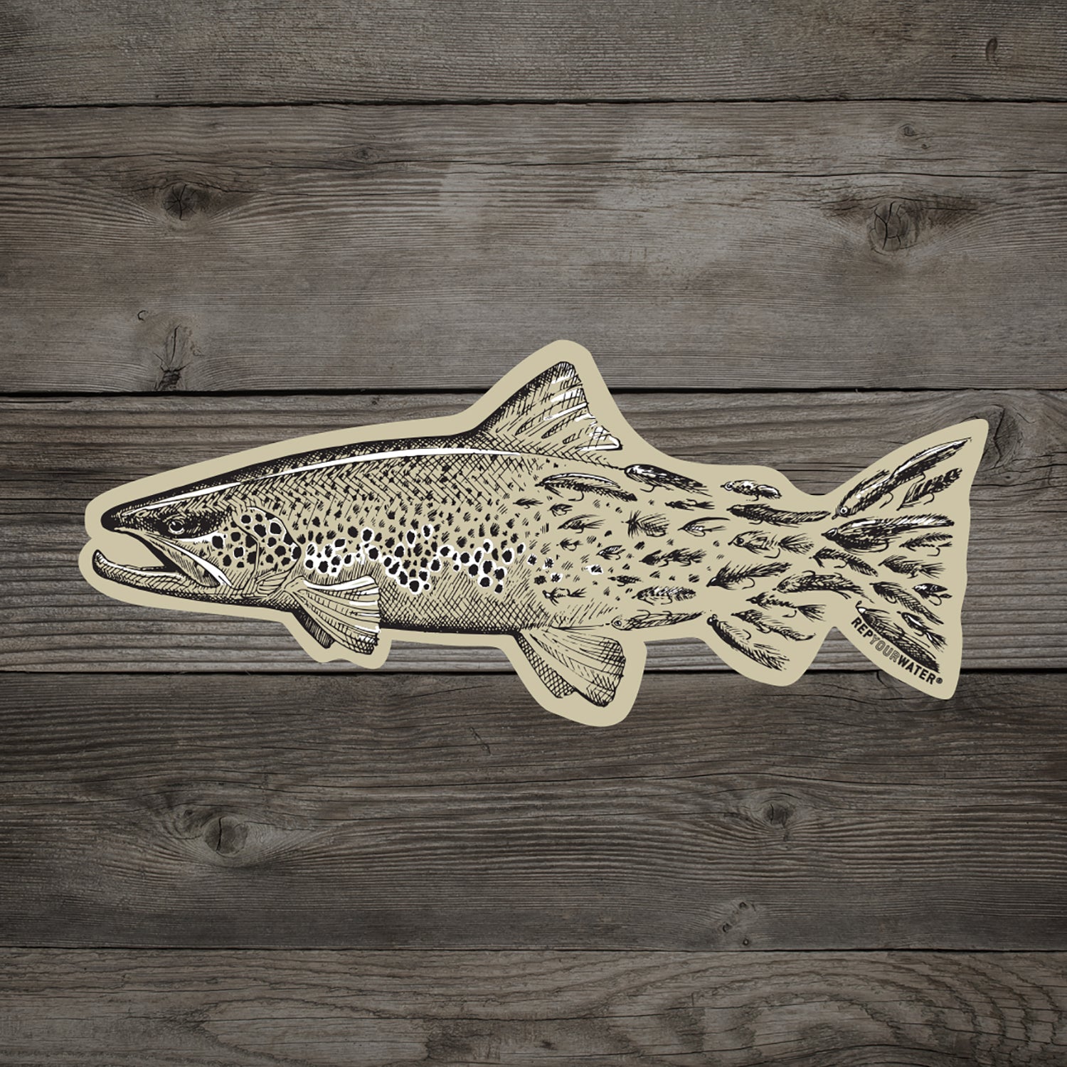 wood background with tan sticker of a brown trout that transitions into fishing flies towards the tail