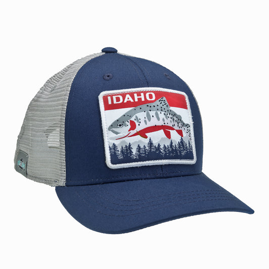 A hat with light gray mesh in the back, navy fabric in the front and a large front patch that says "IDAHO" on it as well as a cutthroat trout and some pine trees and mountains.
