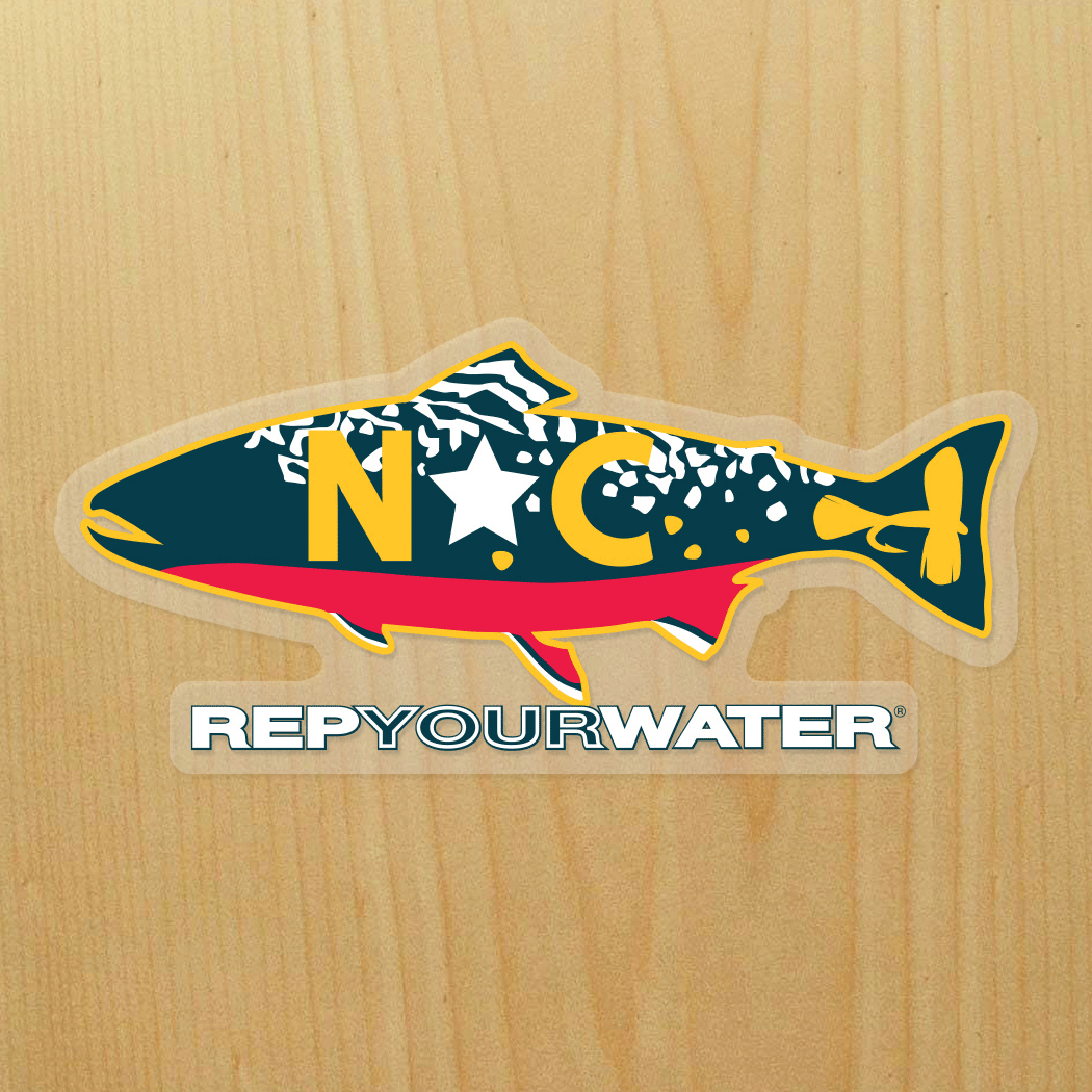 A wood background has a sticker on it that is a brook trout with NC in the middle of it and a fly in the tail.  It reads RepYourWater underneath the trout