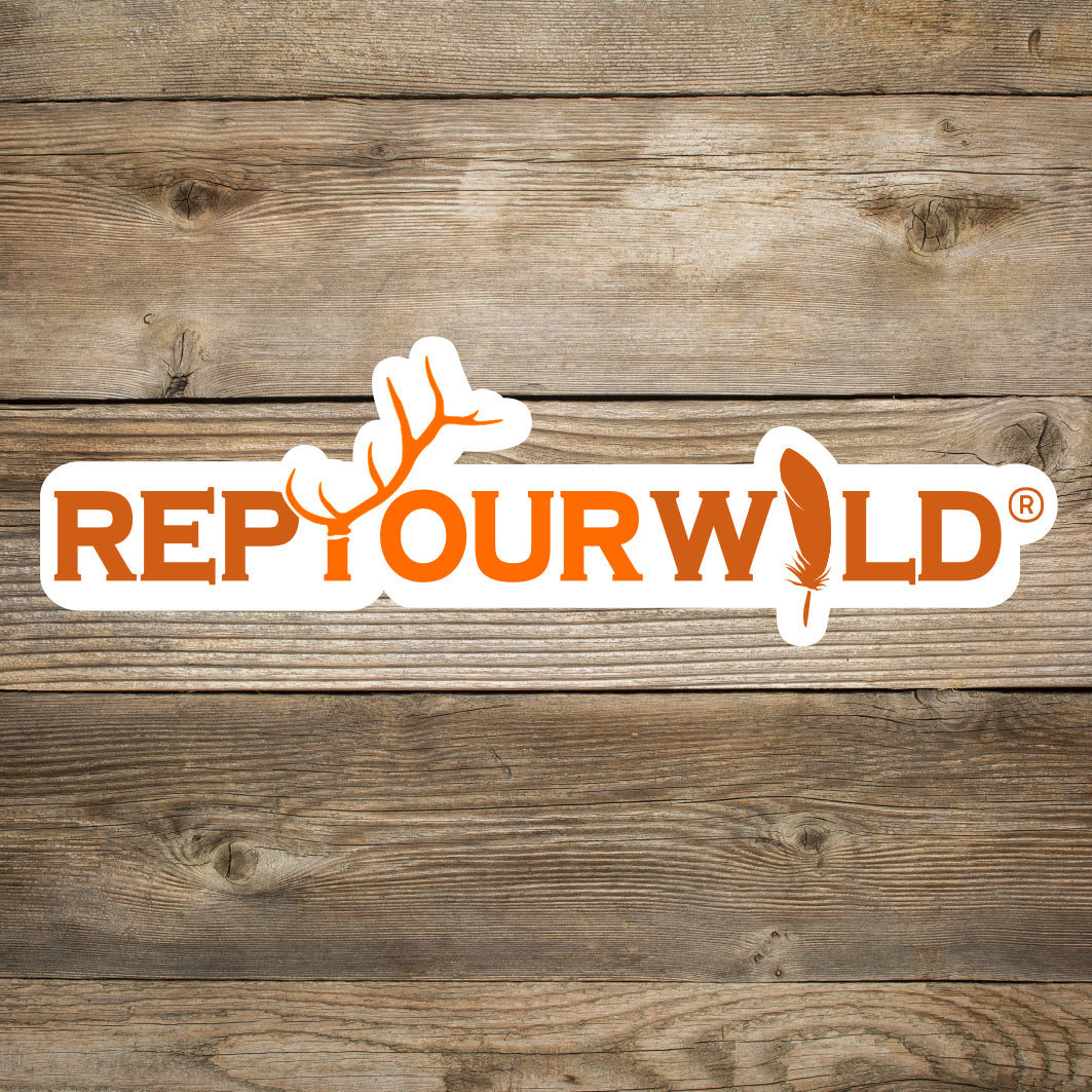 White sticker with orange texts that reads repyourwild with an elk antler and a feather with a wooden background