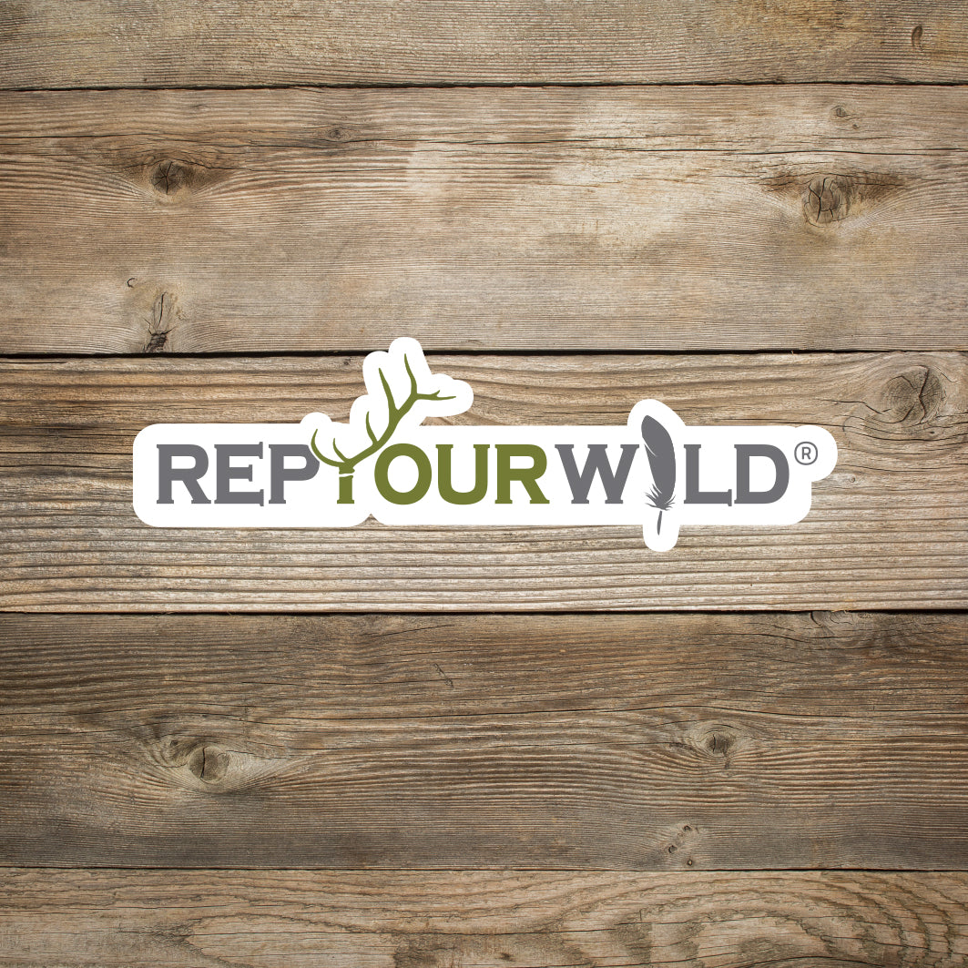 white sticker with grey and green text that reads rep your wild and features an elk antler and a feather on a wood background