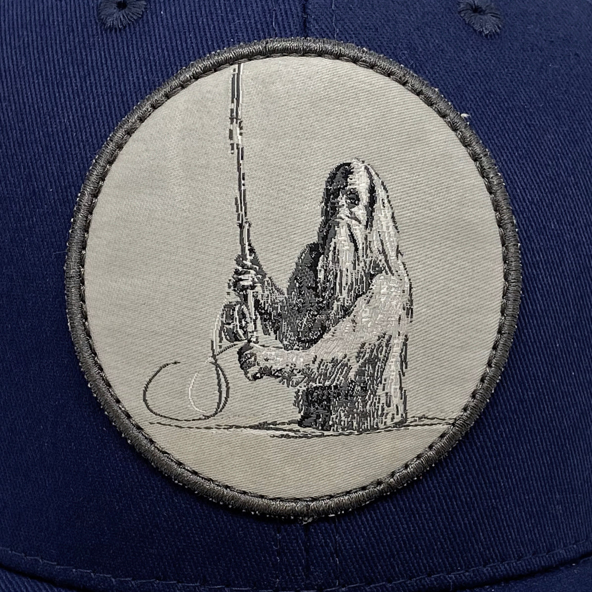 A close up of the patch that features a sasquatch casting a spey rod