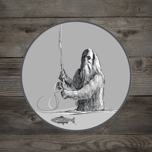 A sticker on a wood background that features a sasquatch casting a spey rod