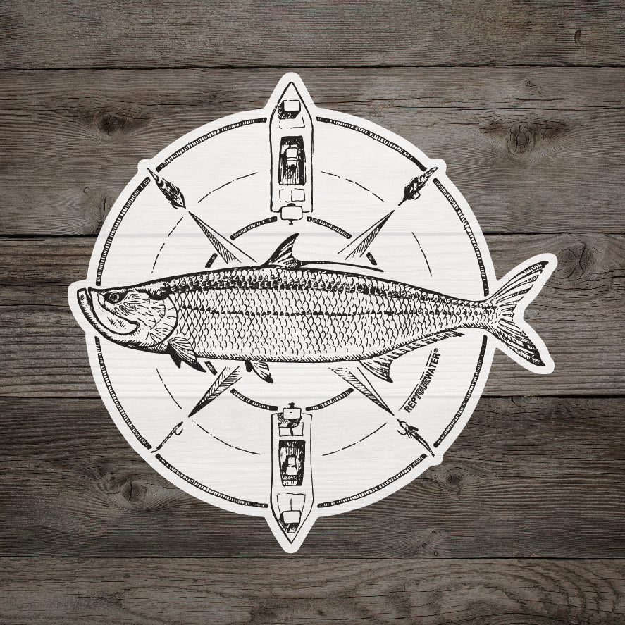 A sticker on a wood background that features drawing of a tarpon in the middle of a compass that has flies and drift boats featured on it